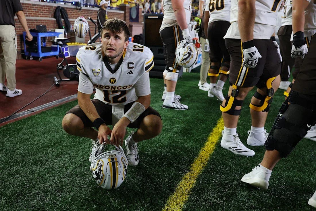 A Western Michigan football player crouching on the sideline after a close loss